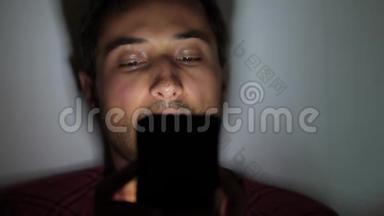 人类`的脸在黑暗中被智能手机屏幕照亮。 晚间社交媒体谈话